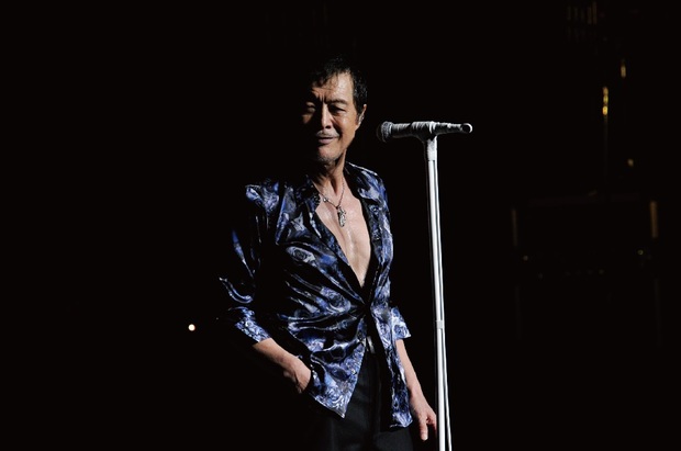 青いシャツを着てポケットに手を入れている矢沢永吉の画像